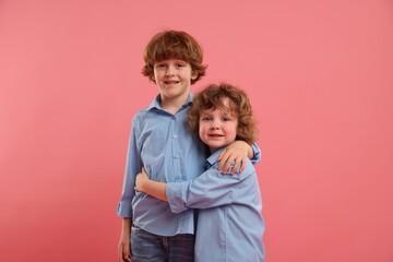 Cute little brothers hugging on pink background