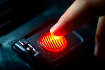 Finger pressing illuminated red button on electronic device