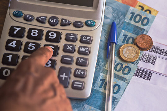 Real - Brazilian currency. Real notes on a wooden table with a calculator and pen in the composition. Concept of economy, finance, Selic rate, taxes and financial planning