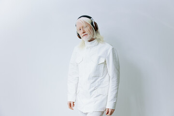 Elegant portrait of a person with long white hair wearing headphones and a stylish white outfit against a minimalistic light background Modern and artistic concept