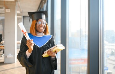 Portrait of African American graduate student in toga holding her diploma