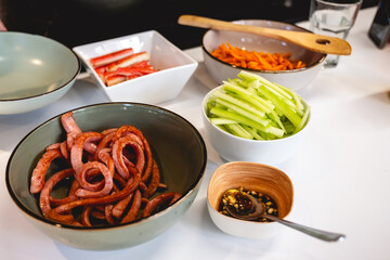 Colorful bowls and plates filled with authentic kimbap ingredients on white kitchen counter...