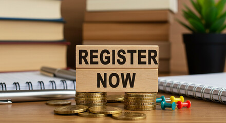 Close up of register now sign with spiral notebook coins and plant showing registration announcement
