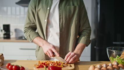 Guy hands slicing ingredients at kitchen listening music in headphones closeup.