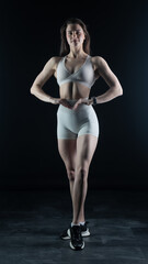 Fototapeta premium Young beautiful woman with athletic body on dark background. Fitness girl