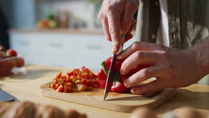 Cook hands slicing pepper on chopping board home kitchen closeup. Man preparing