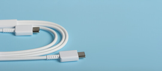 White USB Type-C charging cable on light blue surface with copy space