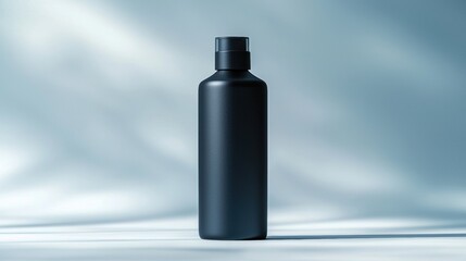Sleek black bottled container with matte finish standing on smooth reflective surface against soft blue background, minimalistic modern design for packaging