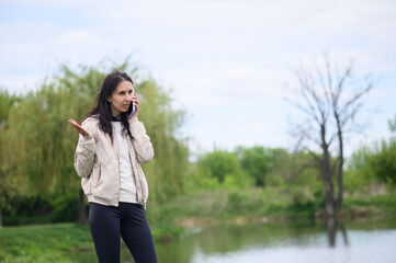 Smiling woman making a video call in park and pointing upward
