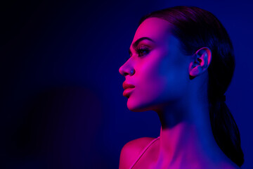Stylish young woman with vibrant pink and blue neon lighting in a modern fashion studio setting