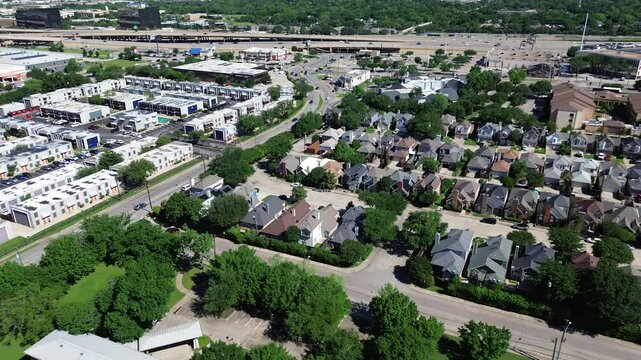 Busy Interstate 635 highway overpass stack interchange through rapid growing North Dallas mixed use development of warehouse, restaurant, residential houses, large apartment complex rental units