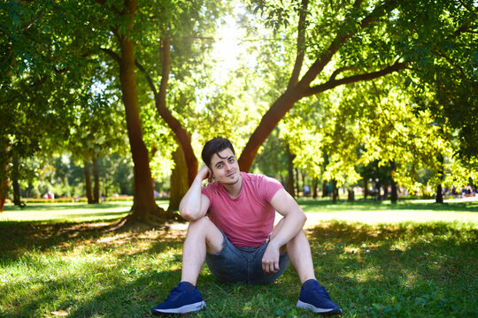 Young Man Sitting Relaxed Alone in Sunny Park