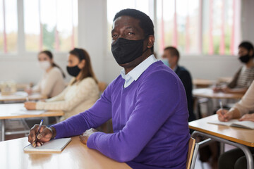 Portrait of adult aframerican man in protective face mask during lesson in extension school. Concept of necessary precautions and social distancing in coronavirus pandemic