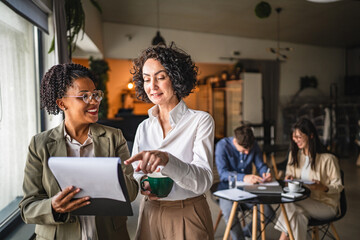 two multicultural businesswoman colleagues read and analysis document
