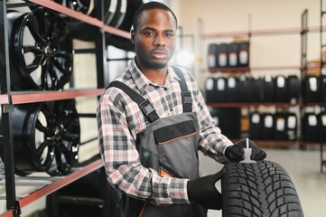 A professional African american worker in a car service measures the tread diameter of a wheel with...