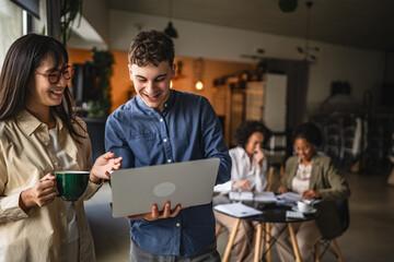 two diverse young entrepreneurs work on laptop in office