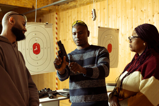 Shooting range safety officer teaching students how to cock pistol before firing. Firing range instructor providing comprehensive framework to achieve high level of proficiency with weapons