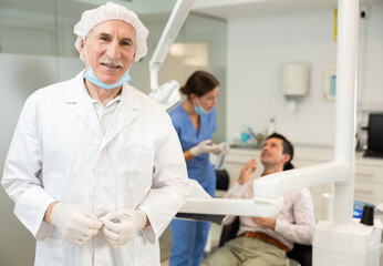 Obraz premium Mature man dentist posing while examining patient in dental clinic