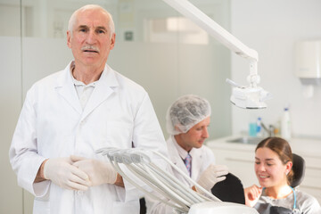 Obraz premium Senior man dentist doctor in white coat cooperates with clinic, works as general practitioner in dental department of clinic. Doctor enjoys working in profession.