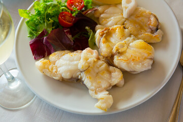 Healthy eating. Baked pieces of monkfish with lemon and salad of greens and cherry tomatoes