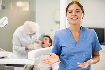 Fototapeta premium In dentists office, girl nurse before start of appointment and working day. Positive medical specialist welcomes clinics clients. Doctor enjoys working in profession. Patient treatment in background