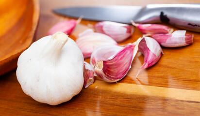 Whole garlic with separated cloves lying on a wooden table. Close-up image..
