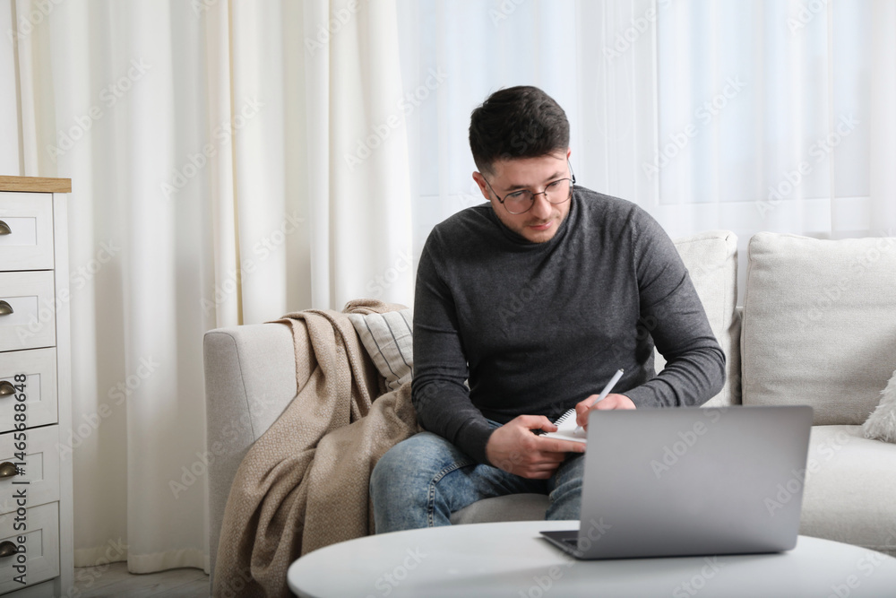 Poster man taking notes during online lesson at table indoors, space for text. self-study