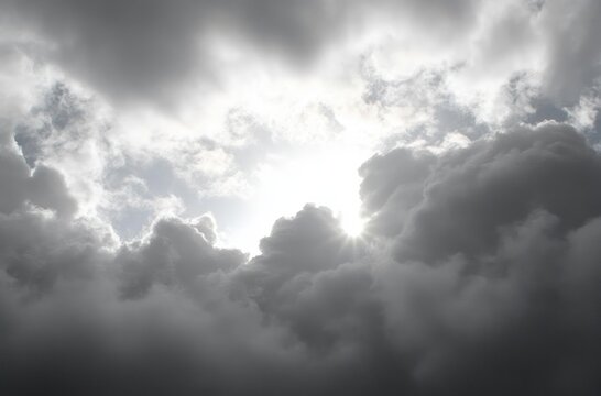 Bright sunlight breaking through dense dark clouds in a dramatic and moody sky