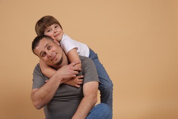 Father and his son on beige background, space for text