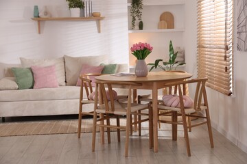 Stylish dining table with chairs and comfortable sofa in room. Interior design