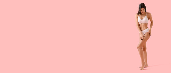 Young woman in underwear with cellulite problem on pink background