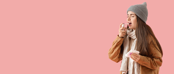 Ill young woman with inhaler on pink background