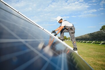 Indian man in uniform on solar farm. Competent energy engineer controlling work of photovoltaic cells