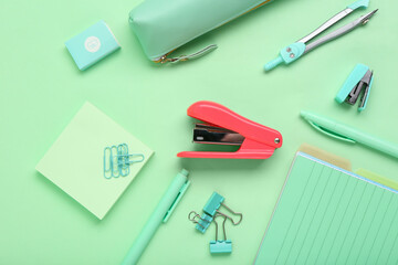 School supplies with stapler on green background