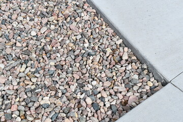 Pea gravel around sidewalk. Corner of sidewalk.