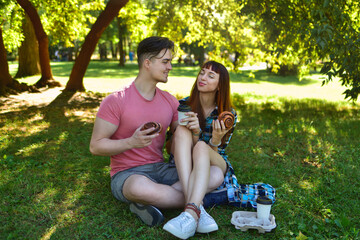 Happy Young Couple Enjoying Picnic Treats in Park