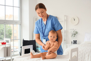 Young nurse with newborn baby on table in maternity hospital
