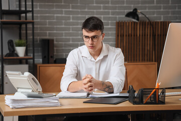 Worried young man at workplace in office