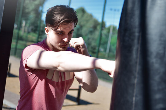 Young Man Striking Punching Bag During Outdoor Boxing Workout
