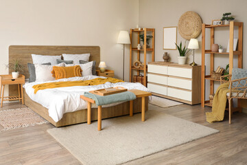 Interior of stylish bedroom with shelving units and standard lamp near cozy bed