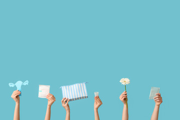 Many female hands with menstrual pads, cosmetic bag and paper uterus on blue background