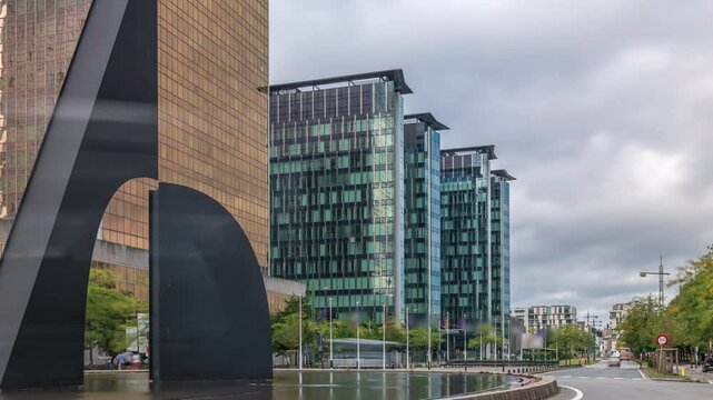 Timelapse of a fountain in a roundabout near Brussels North Station. Traffic flows around the intersection of Boulevards Simon Bolivar and Roi Albert II surrounded by modern glass skyscrapers. Belgium