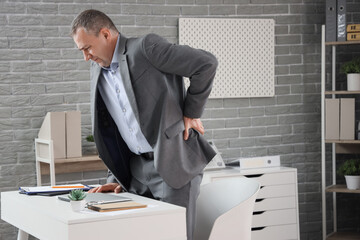 Mature businessman suffering from back pain in office