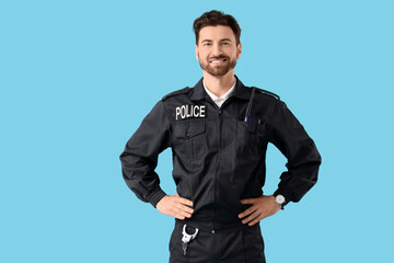 Happy male police officer with radio transmitter and handcuffs on blue background