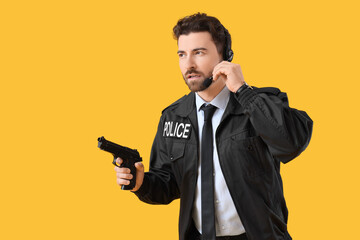 Male police officer in headset with gun on yellow background