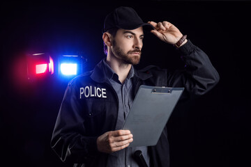 Male police officer with clipboard against flashing siren lights on black background