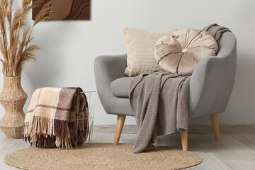 Interior of stylish living room with armchair, basket and plaids