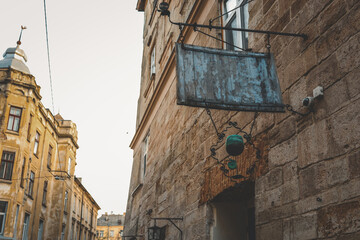 Rustic metal sign of Cafй Sophie hanging on a historic stone building in an old European city street, surrounded by vintage architecture and warm evening light