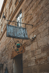 Rustic metal sign of Cafй Sophie hanging on a historic stone building in an old European city street, surrounded by vintage architecture and warm evening light