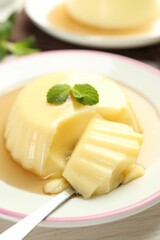 Delicious pudding with caramel sauce and mint served on white table, closeup